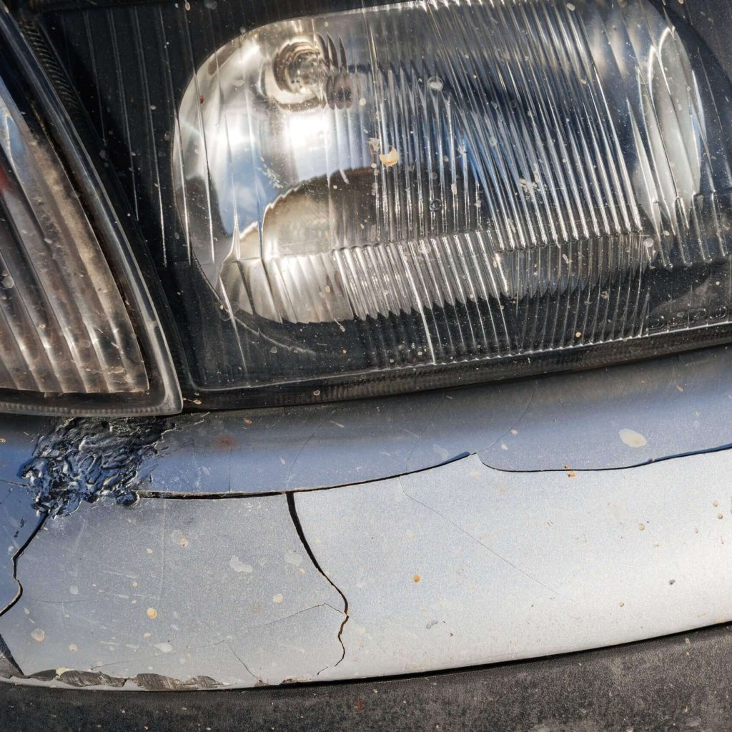 altes-auto-nach-einem-unfall-mit-beschadigter-zerknitterter-stossstange-scaled